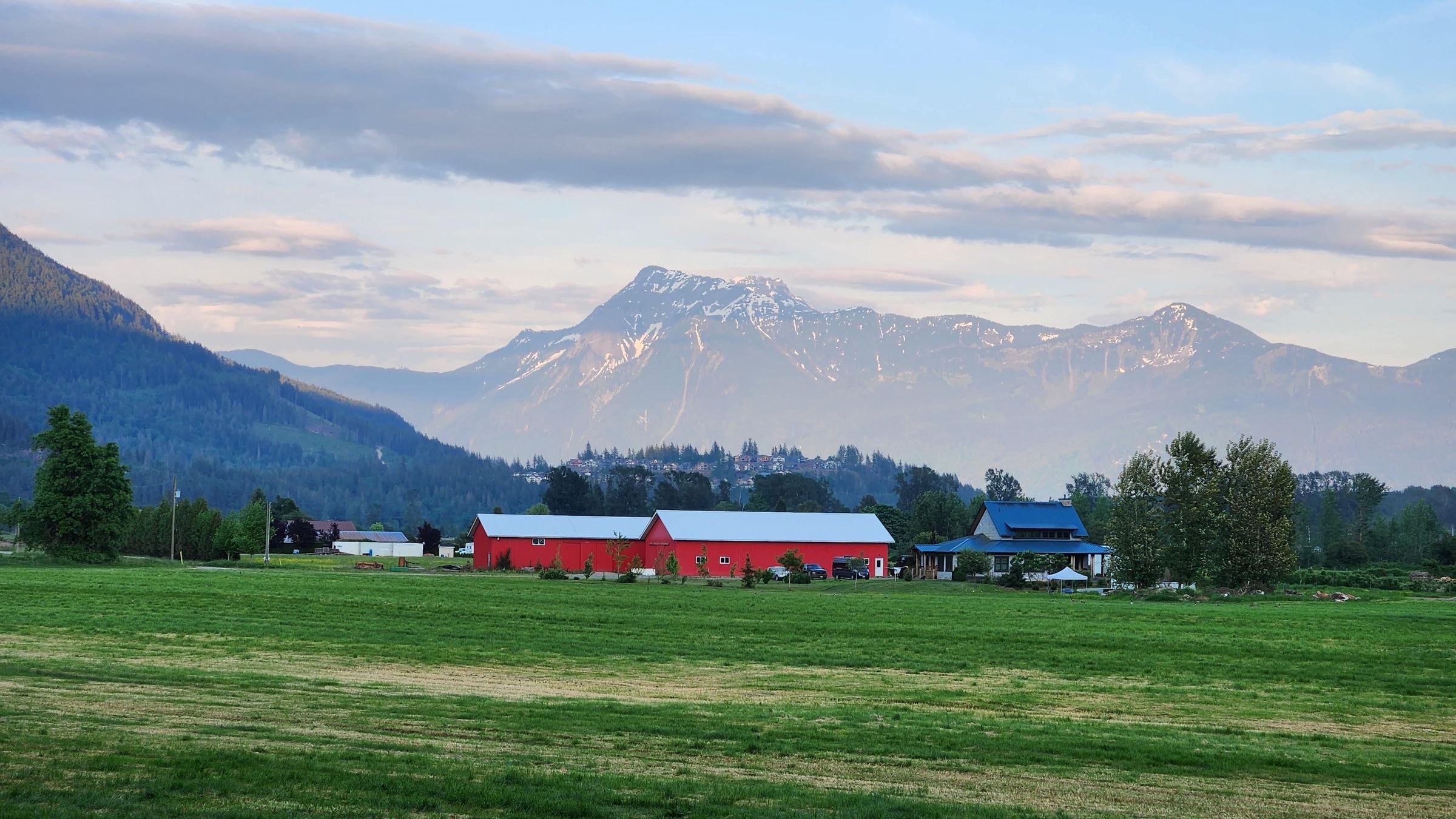 Red farm buildings in a green valley with mountains rising behind them